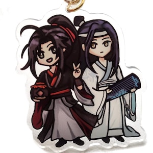 May include: A clear acrylic keychain featuring two anime characters. The character on the left has black hair, a red headband, and is holding a red object. The character on the right has purple hair, a white headband, and is holding a blue and white instrument.