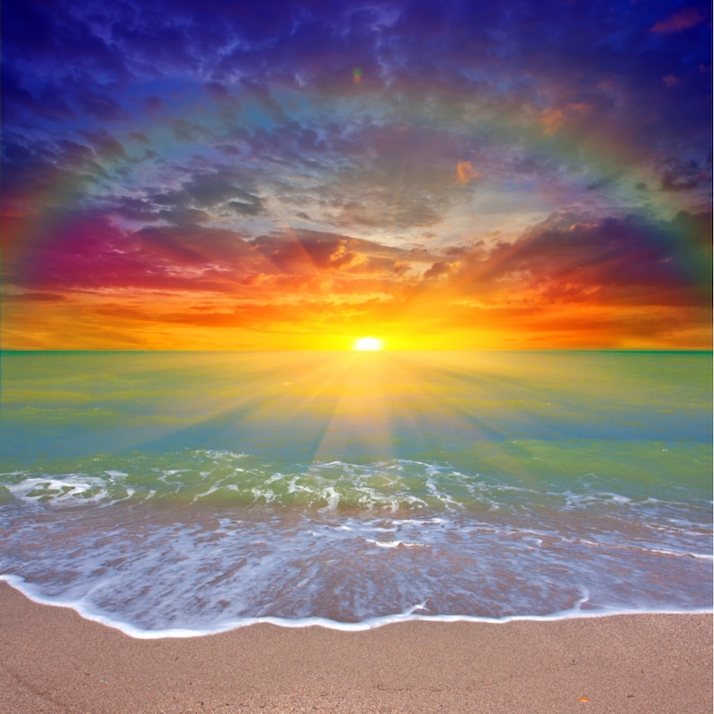 May include: A vibrant sunset over the ocean. The sky transitions from deep blue to fiery orange and red, with the sun's rays illuminating the water. Gentle waves lap the sandy shore, creating a serene and colorful coastal scene.
