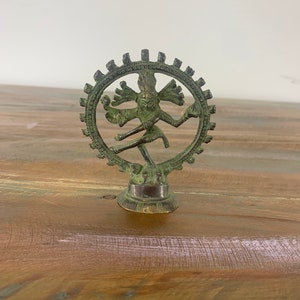 May include: A green metal statue of Shiva Nataraja, the Hindu god of dance, in a circular pose with multiple arms. The statue is on a round base.