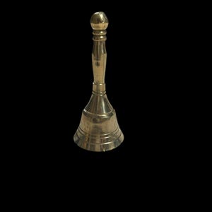 Pode incluir: Um pequeno sino dourado com o topo arredondado e a base alargada. O sino &eacute; feito de metal e tem um acabamento liso e polido.