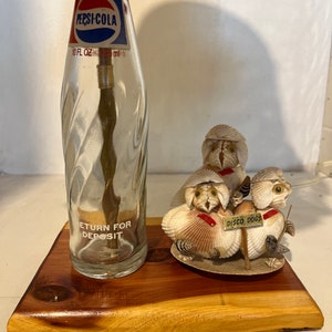 Recycled old 10 oz pepsi bottle on a cedar base w/ a homemade out of sea shells a group of three dico dogs.