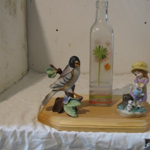 recycled bottle w/ flowers painted on it.Has bird figurine & a little girl w/ a watering can