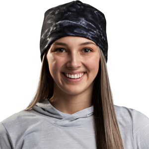 May include: A woman wearing a gray hooded sweatshirt and a black and white tie-dye beanie.