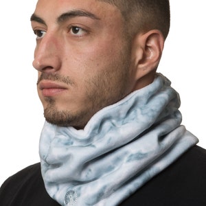 May include: A white and blue patterned fleece neck warmer with a small circular logo.