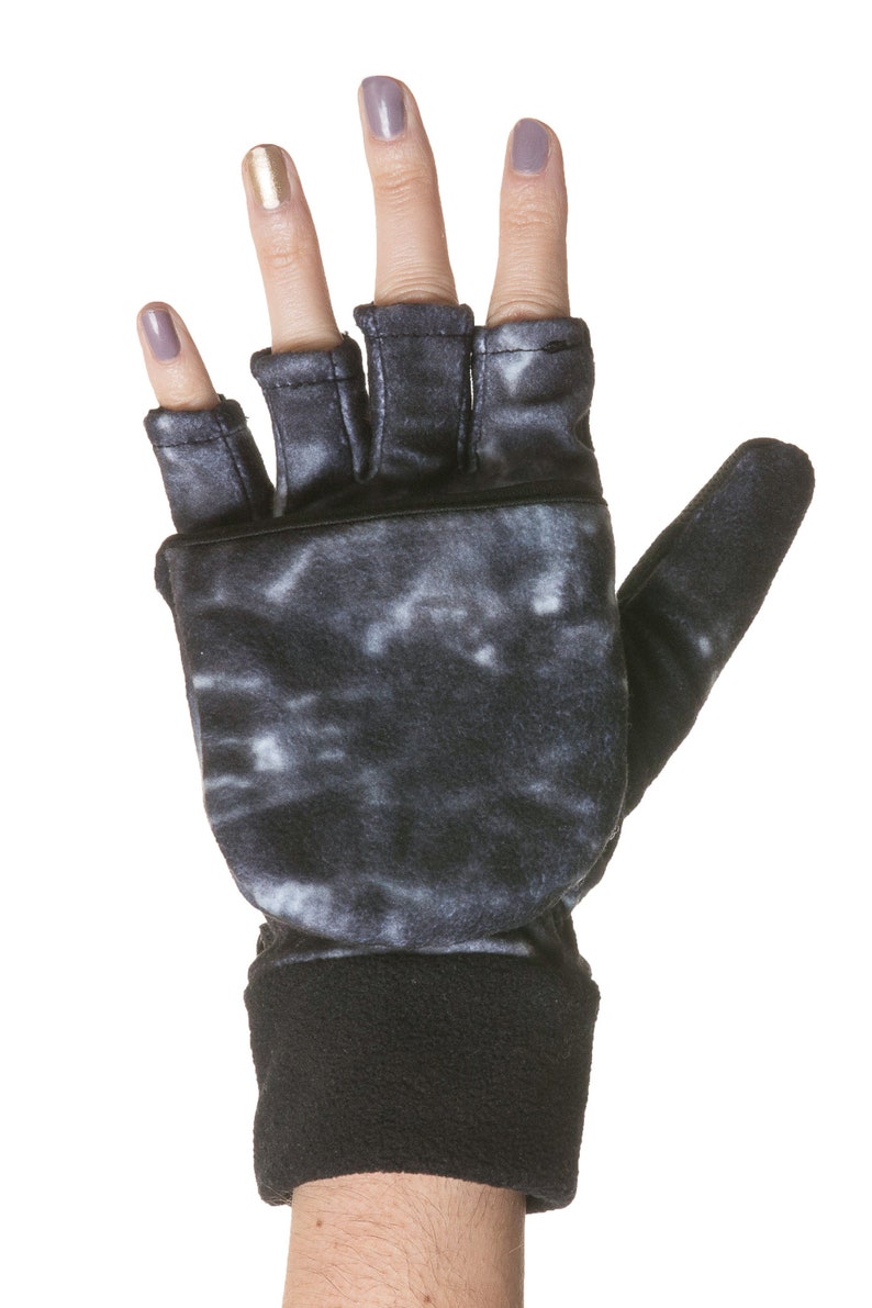 K&ouml;nnte beinhalten: Fingerlose Handschuhe in Schwarz und Wei&szlig; mit Batik-Muster und einem schwarzen Fleece-Bund. Die Handschuhe haben ein fingerloses Design mit einem Daumenloch.