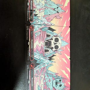 May include: Four collectible trading cards depicting a mountain landscape with a skull and other fantasy elements. The cards have a pink, blue, and white colour scheme with the word "Mountain" printed on them. The cards are from the "Wizard of the Coast" series.