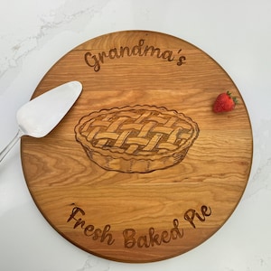 May include: Round wooden pie server with the text "Grandma's Fresh Baked Pie" and a drawing of a pie.