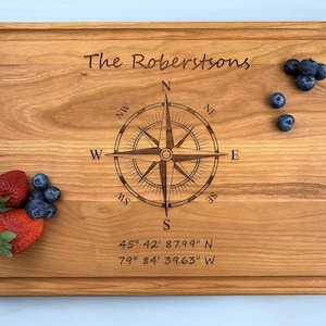 May include: A wooden chopping board with a compass design and the text "The Robertsons" engraved on it. The coordinates "45° 42' 87.99" N 79° 84' 39.63" W" are also engraved on the board.