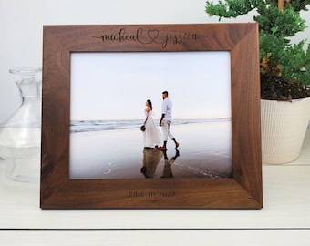 May include: A brown wooden picture frame with a photo of a couple on a beach. The frame is engraved with the names "micheal & jessica" and the date "JUNE 10, 2022".