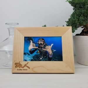 May include: A wooden picture frame with a scuba diver photo inside. The frame has a carved scuba diver design and the text "Scuba Steve" below it.