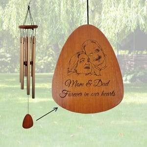 May include: A wind chime featuring a circular wooden top, multiple metallic tubes, and a teardrop-shaped wooden pendant. The pendant is engraved with a line drawing of two people and the text "Mom & Dad Forever in our hearts."