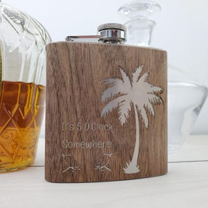 May include: A wooden flask with a stainless steel top and a palm tree design. The flask is engraved with the text "It's 5 O'Clock Somewhere" and two lounge chairs.
