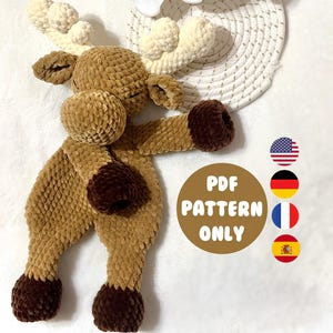 Puede incluir: Un juguete de reno de ganchillo en marrón y crema. El reno tiene una cabeza redonda, grandes cuernos y un cuerpo largo con pezuñas marrones oscuras. El texto "PDF PATTERN ONLY" está en un círculo marrón.