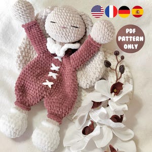 Op de afbeelding: Een handgemaakt, pluche konijn in een stoffige roze onesie met witte accenten en een witte kraag. Het konijn heeft gesloten ogen en uitgestrekte armen. De afbeelding bevat een decoratief bloemstuk en de tekst "PDF PATTERN ONLY".