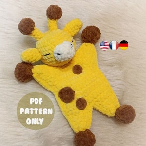 Könnte beinhalten: Ein gehäkeltes Giraffen-Plüschtier mit braunen Flecken und braunen Wollpompons. Die Giraffe liegt auf dem Rücken mit geschlossenen Augen. Der Text "PDF PATTERN ONLY" ist auf dem Bild zu sehen.