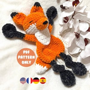 Może przedstawiać: Wzór na szydełku na śpiącego lisa amigurumi. Wzór jest dostępny w języku angielskim, francuskim, niemieckim i hiszpańskim. Lis jest pomarańczowy i biały z czarnymi łapami i białym brzuchem. Wzór jest dostępny tylko w formacie PDF do pobrania.