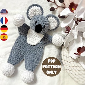 May include: A gray and white crocheted koala amigurumi toy with white pom-poms on the hands and feet. The text "PDP PATTERN ONLY" is on a brown circle in the lower right corner of the image.
