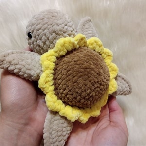 May include: A crocheted stuffed turtle toy with a brown shell and a yellow sunflower design.