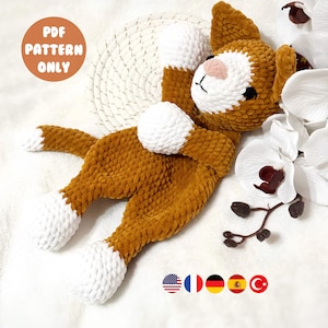 May include: A handmade crochet cat plushie in shades of brown and white, with a pink nose and black eyes. The cat is lying down, with its paws and head visible. The image includes the text "PDF PATTERN ONLY".