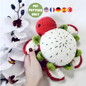 May include: A handmade crochet dragon fruit plushie in red, white, and green. The plushie has a red head, a white body with black seed details, and red and green accents. The image includes the text "PDF PATTERN ONLY".