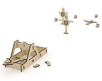 May include: A wooden catapult toy with a yellow rubber band and a small wooden ball. The catapult is designed to launch the ball at targets, which are also made of wood and feature a bullseye design. The targets are standing upright on a white surface.