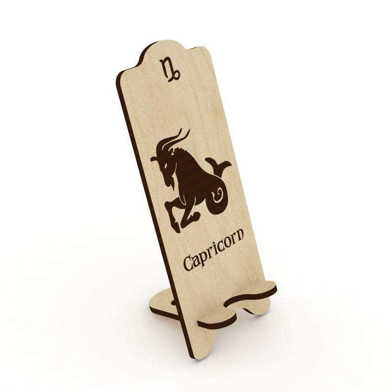 May include: Wooden phone stand with a cutout of the Capricorn zodiac sign and the word "Capricorn" below it.
