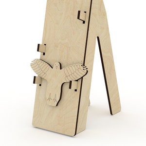May include: A wooden easel with a bird cutout design. The easel is made of light brown wood and has a simple, minimalist design.