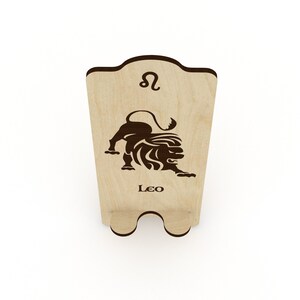May include: Wooden phone stand with a laser-cut design of the Leo zodiac symbol and the word "Leo".