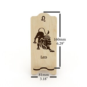 May include: Wooden phone stand with a laser-engraved Leo zodiac sign and the word "Leo". The stand is 6.29 inches tall and 3.18 inches wide.