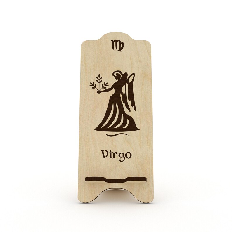 May include: Wooden phone stand with a Virgo zodiac sign and the symbol for Virgo. The stand is light brown and has a cutout for a phone.