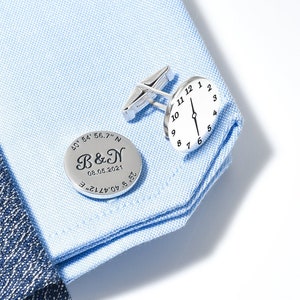 Può includere: Gemelli in argento con un design rotondo. Un gemello presenta il testo "B&N" e la data "08.06.2021" con coordinate. L'altro gemello presenta un quadrante dell'orologio.