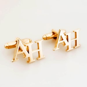 May include: A pair of gold cufflinks with the letters "AH" engraved on them.