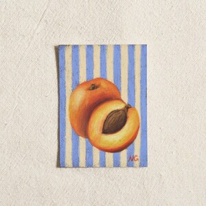 Può includere: Un dipinto rettangolare raffigurante due albicocche arancioni, una intera e una tagliata a metà con un nocciolo marrone visibile, su uno sfondo a strisce verticali azzurre e color crema. Le iniziali NG dell'artista sono dipinte in rosso in basso.