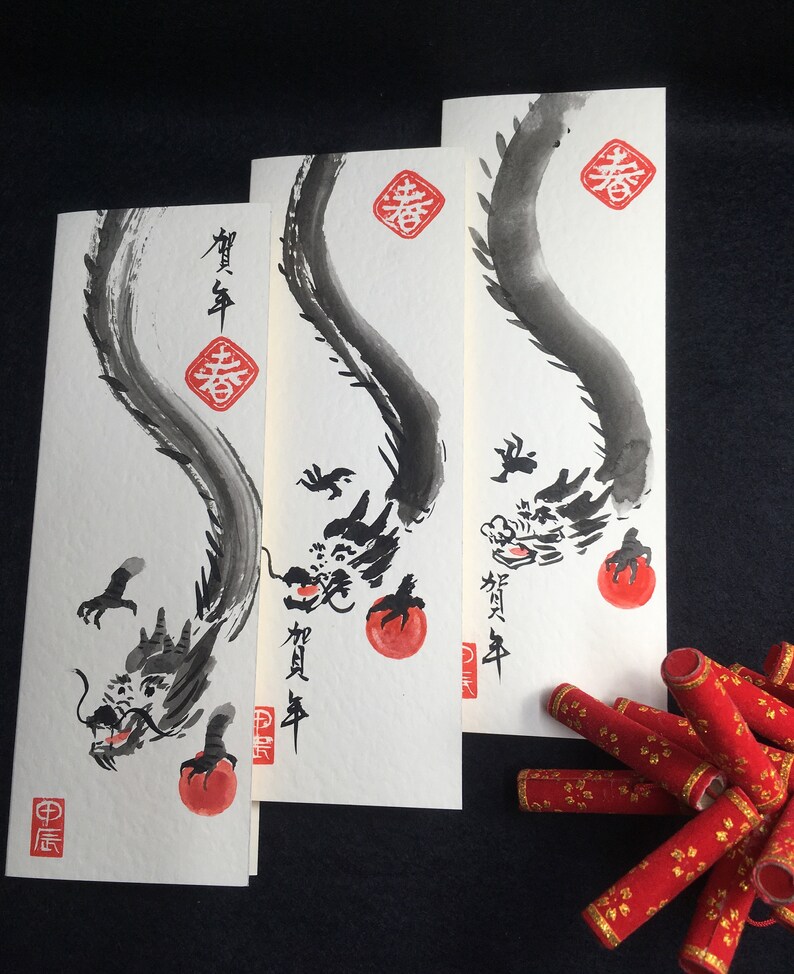 Puede incluir: Tres pinturas de tinta negra de dragones sobre papel blanco con caracteres chinos rojos. Los dragones est&aacute;n enroscados con sus colas en sus bocas. Los caracteres son "Primavera" y "Feliz A&ntilde;o Nuevo".
