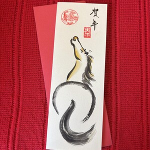 K&ouml;nnte beinhalten: Eine Gru&szlig;karte mit einer Aquarellillustration eines Pferdes in Schwarz, Gelb und Wei&szlig;, mit japanischer Kalligraphie und einem roten Siegel. Die Karte liegt auf rotem Hintergrund, mit einem roten Umschlag.