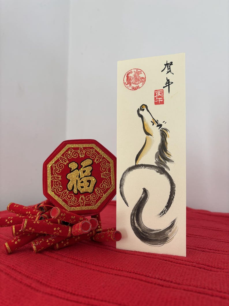 K&ouml;nnte beinhalten: Chinesische Neujahrsdekorationen in Rot und Gold. Enth&auml;lt eine achteckige rote Plakette mit goldenen Buchstaben, eine Karte mit einer Pferdeillustration und rote Feuerwerksk&ouml;rper-Ornamente. Der Hintergrund ist eine rote, strukturierte Oberfl&auml;che.