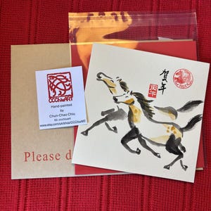 May include: Hand-painted artwork by Chun-Chao Chiu featuring two running horses in black and yellow ink. The artwork includes Chinese characters and a red seal. The image also shows a business card and a kraft paper envelope.