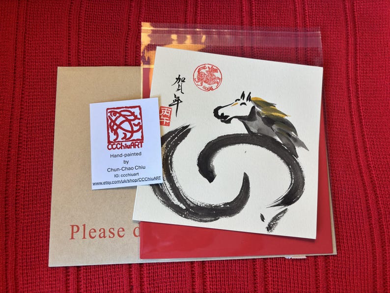 Pode incluir: Uma impress&atilde;o de arte com uma ilustra&ccedil;&atilde;o de cavalo a preto e branco e caligrafia. A impress&atilde;o est&aacute; num cart&atilde;o branco com detalhes em vermelho, acompanhada por um cart&atilde;o de visita e um envelope castanho. O fundo &eacute; tecido vermelho.
