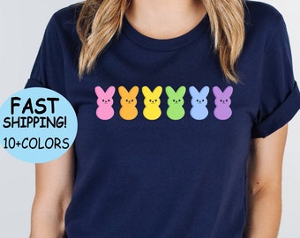 Könnte beinhalten: Ein marineblaues T-Shirt mit einer Reihe von regenbogenfarbenen Marshmallow-Peeps. Das Shirt hat einen Rundhalsausschnitt und kurze Ärmel.