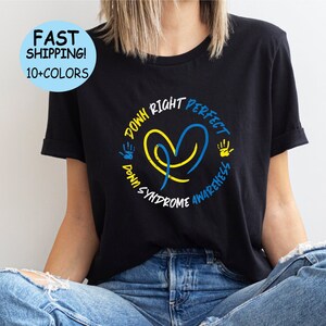 Op de afbeelding: Zwart T-shirt met een hartvormig ontwerp van een blauw en geel lint en de tekst "Down Right Perfect Down Syndrome Awareness".