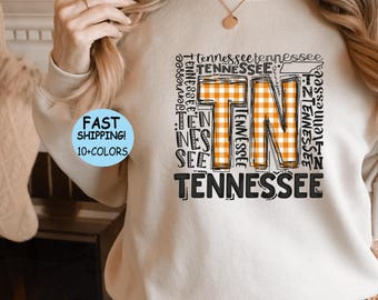 Puede incluir: Una sudadera blanca con un diseño gráfico que presenta el estado de Tennessee en un patrón a cuadros y la palabra "Tennessee" repetida varias veces.