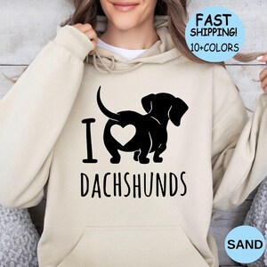 May include: A beige hoodie with a black graphic of a dachshund with a heart on its rear end. The text "I love dachshunds" is printed below the graphic.