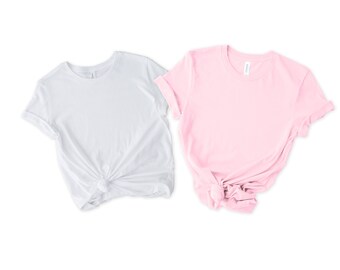 May include: Two blank t-shirts, one white and one light pink, are knotted and laid out on a white background.