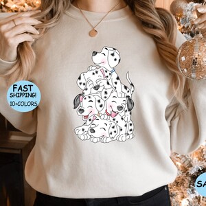 Puede incluir: Sudadera beige con una ilustraci&oacute;n de cachorros d&aacute;lmatas. Los cachorros, con manchas negras, est&aacute;n apilados unos sobre otros y sonriendo. La sudadera tiene el texto "FAST SHIPPING! 10+ COLORS" y la palabra "SAND".