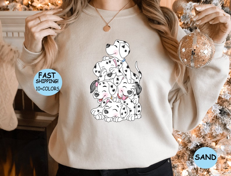 Puede incluir: Sudadera beige con una ilustraci&oacute;n de cachorros d&aacute;lmatas. Los cachorros, con manchas negras, est&aacute;n apilados unos sobre otros y sonriendo. La sudadera tiene el texto "FAST SHIPPING! 10+ COLORS" y la palabra "SAND".