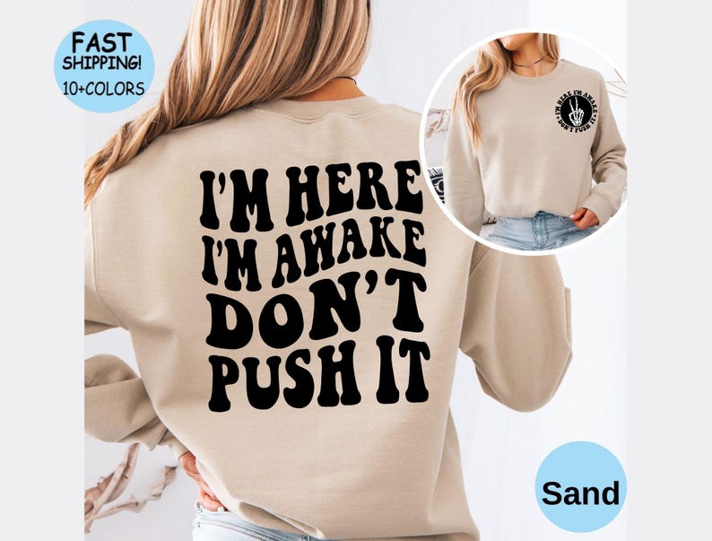 May include: Sand colored sweatshirt with the text "I'm here I'm awake Don't push it" printed in black.