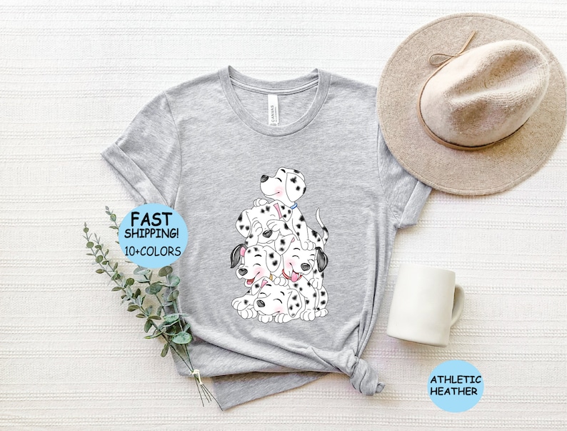 Puede incluir: Camiseta gris claro con una ilustraci&oacute;n de dibujos animados de cachorros d&aacute;lmatas. Los cachorros tienen manchas negras y est&aacute;n apilados uno encima del otro. La camiseta tiene el texto "FAST SHIPPING! 10+ COLORS" y "ATHLETIC HEATHER".