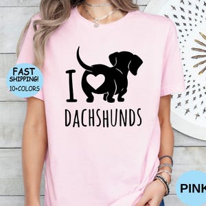 May include: Pink t-shirt with a black silhouette of a dachshund with a heart in its rear end and the text "I love dachshunds".
