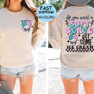 May include: A light beige sweatshirt with a volleyball graphic on the front and the text "If you want a SOFT SERVE GET SOME ICE CREAM" on the back. The text is in a retro style with pink, blue, and green colors.