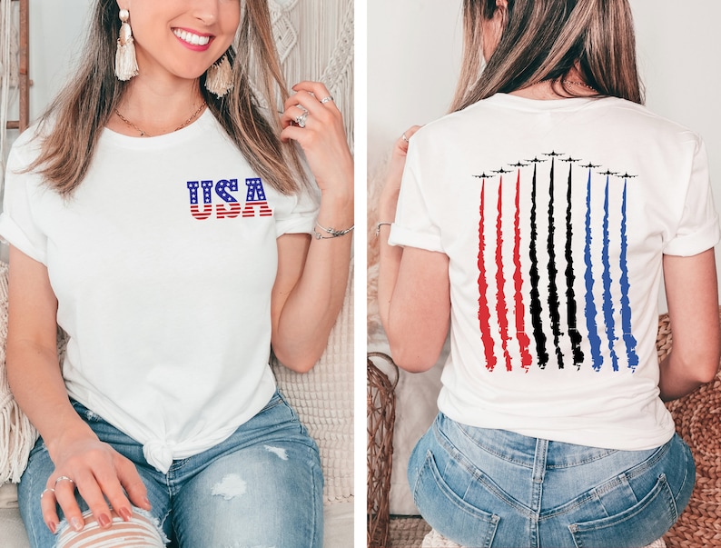 May include: White t-shirt with a red, white, and blue USA graphic on the front and a graphic of red, white, and blue jets flying in formation on the back.